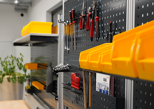 Werkzeughalterung an einer Lochwand mit verschiedenen Handwerkzeugen, gelben Aufbewahrungsboxen.